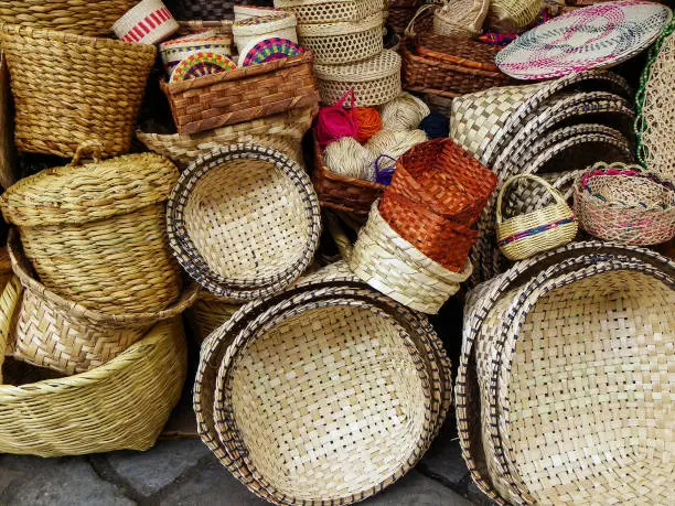 Variety of handmade traditional woven baskets, place mats, panama hats made from straw and natural fiber for sale at the outdoor market in Cuenca, Ecuador