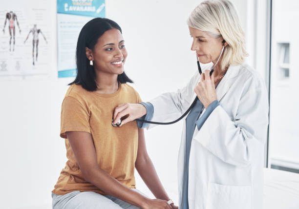 shot of a doctor examining a woman with a stethoscope - visita imagens e fotografias de stock