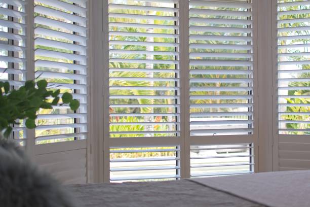 Plantation shutters - selective focus Luxury white plantation shutters in bedroom shutter stock pictures, royalty-free photos & images
