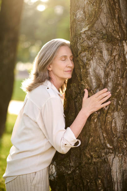istock Woman with closed eyes touching tree 1333500993
