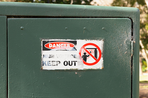 Danger, kelectricaleep out sign on a green box.