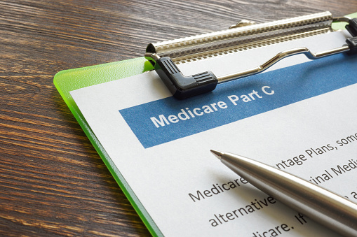 Medicare part C insurance papers with clipboard and pen.