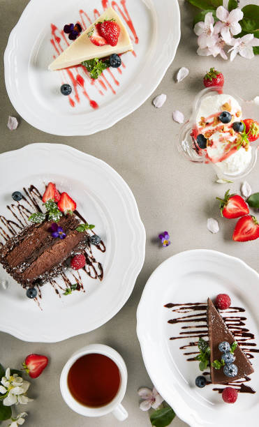 istock Dessert Table - created with Chocolate Cake, Classic Cheesecake and Chocolate Cheesecake. Fresh spring flowers on vintage table with berries and tea cup. Cake slice topped with berries and chocolate sauce. 1333511548
