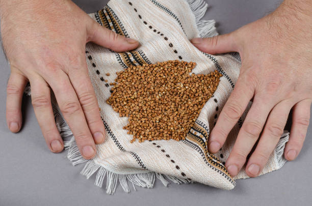 乾燥した茶色の調理されていないそばの穀物は、白い民族のフリンの上にあります - palm people white brown ストックフォトと画像