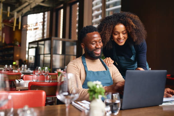 small business owners using laptop in restaurant - family business stockfoto's en -beelden