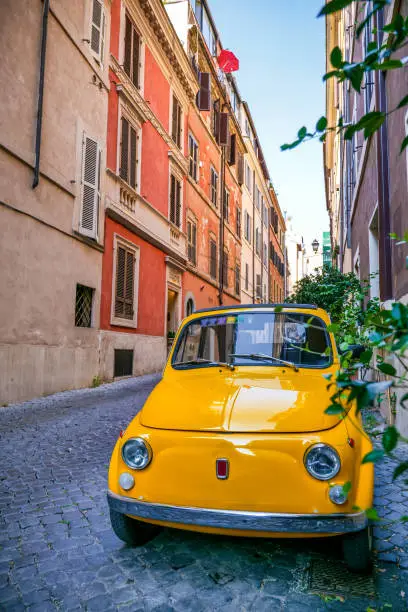 A beauty yellow vintage car parked in the Monti district in historic heart of Rome