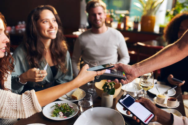 amigos que pagan sin contacto en el restaurante - pagar fotografías e imágenes de stock