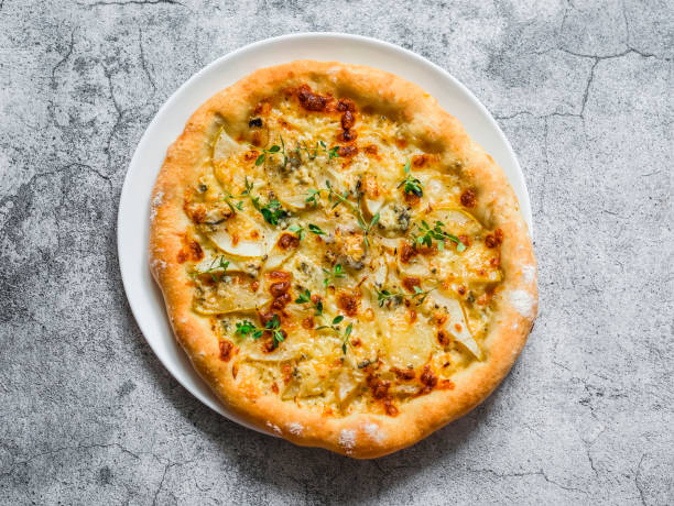 istock Homemade thin crispy flatbread pizza with gorgonzola and pear on a gray background, top view 1333514646