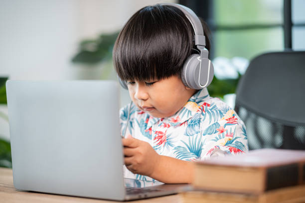 istock asian thai boy with headphones using laptop at table in room at home 1333515532
