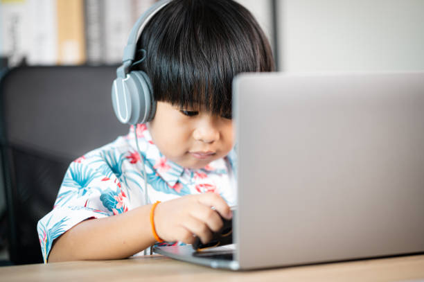 istock asian thai boy with headphones using laptop at table in room at home 1333515536
