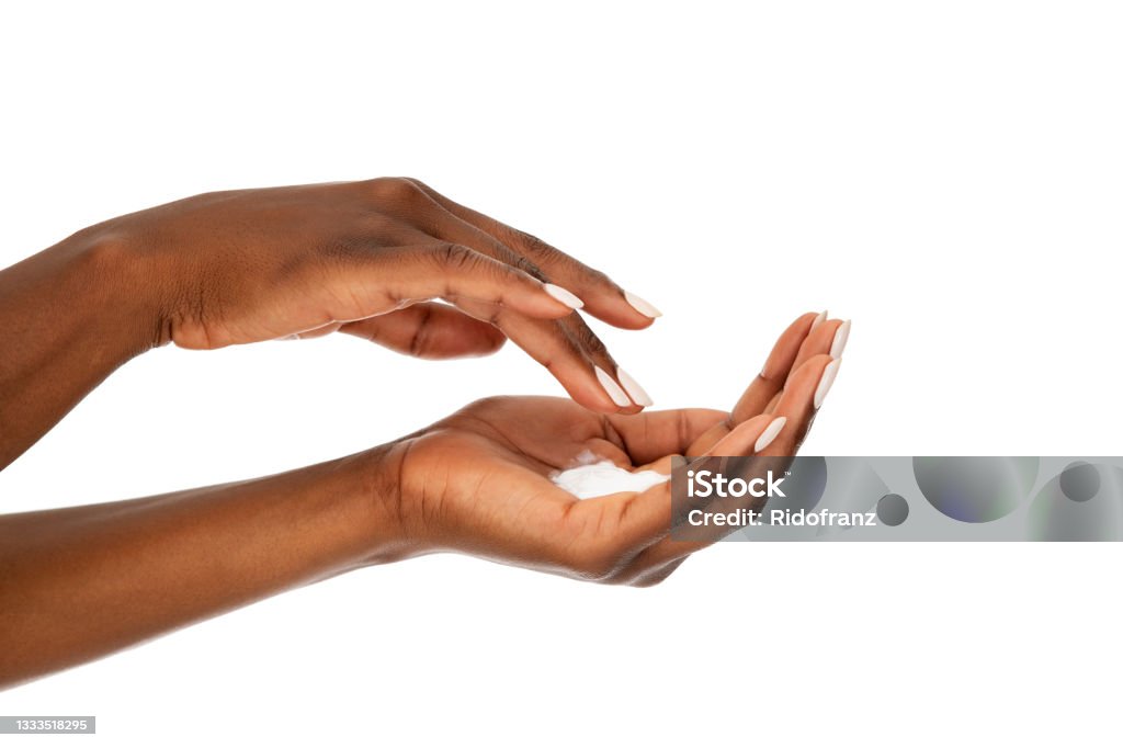 Close up of black woman hands with moisturizer cream Close up of female african woman applying organic cream on hand. Detail of hands of ethnic woman with hand lotion isolated against white background. Side view of black hands with beauty cream: skin care and manicure concept. Hand Stock Photo