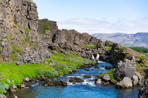Thingvellir national park landscape with river running through and small waterfall at the end. It is known as the Mid-Atlantic Ridge, a boundary between two tectonic plates, the Eurasian and the North Americans  and is product of earth movements. It is UNESCO World Heritage Site.