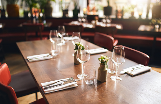 modern set wedding tables in a restaurant with white tablecloths and berry colored flowers