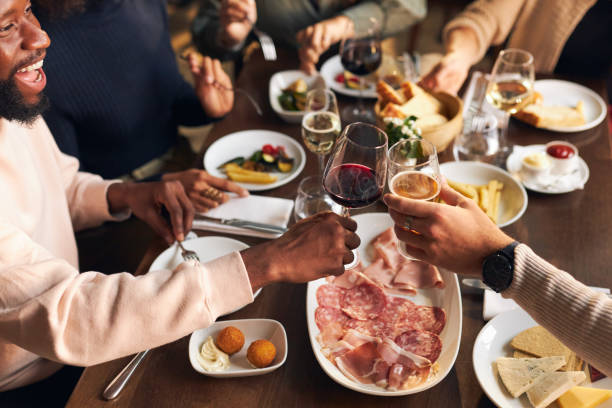 Friends toasting at dinner in restaurant Friends toasting at dinner in restaurant happy hour stock pictures, royalty-free photos & images