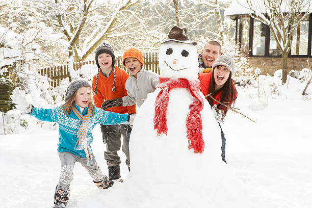famiglia, costruzione di pupazzi di neve nel giardino - snowman snow winter fun foto e immagini stock