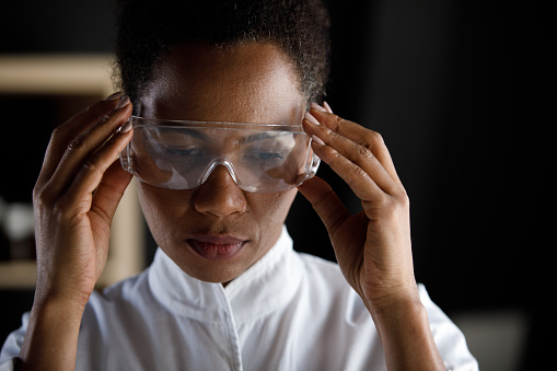Copy space shot of serious female laboratory technician preparing to work and putting on a pair of protective eyeglasses beforehand.