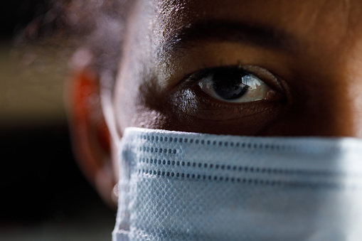 Close up shot of serious African American woman wearing a protective face mask and looking at camera.