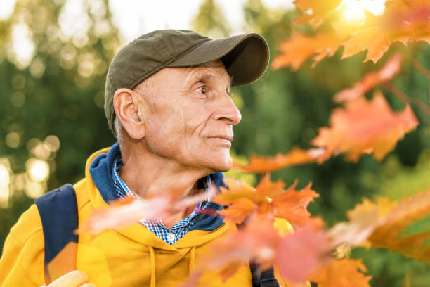 istock Side view close portrait of old authentic man with maple leaves foreground. 1333530091
