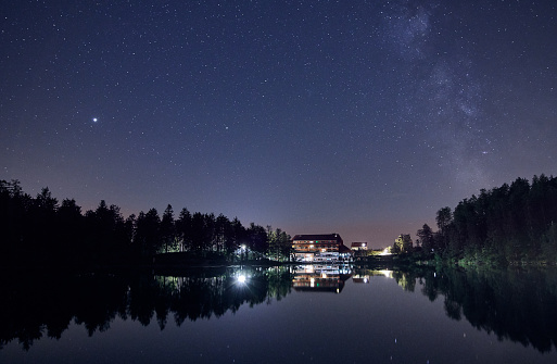 Night sky with star field and milky way over lake Mummelsee in Seebach, Black Forest, Germany, Europe.