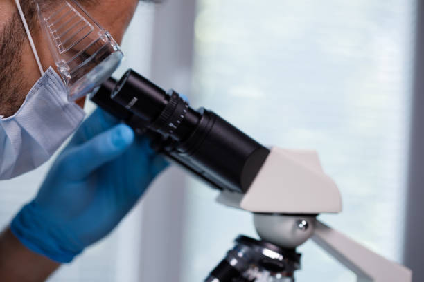 istock Headshot of male lab tech looking at samples under a microscope 1333532107