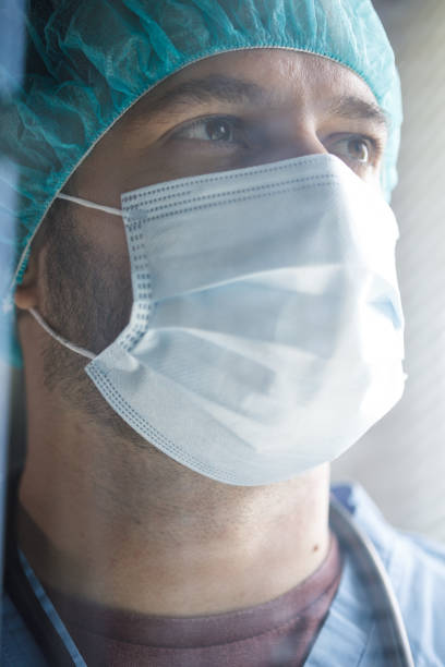 istock Headshot of surgeon in a protective face mask looking into the light 1333532410