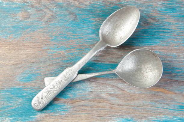 istock Two old metal spoons on blue wooden background. 1333535569