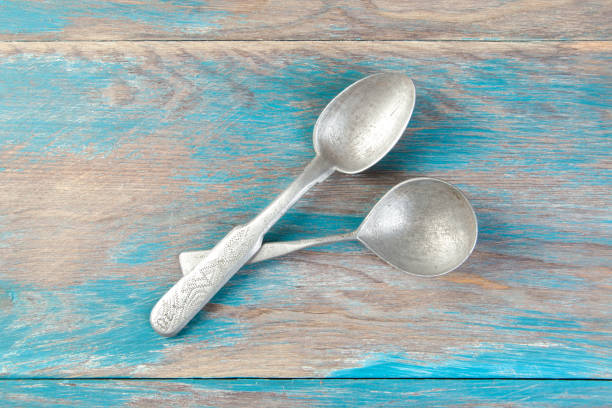 istock Two old metal spoons on blue wooden background. 1333536277