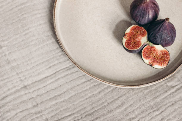 istock Autumn breakfast in bed composition. Blank greeting card mockup, cup of coffee and fig fruit on ceramic plate. White linen background. Velvet cushions and leather bag. Thanksgiving, fall. Top view. 1333541220