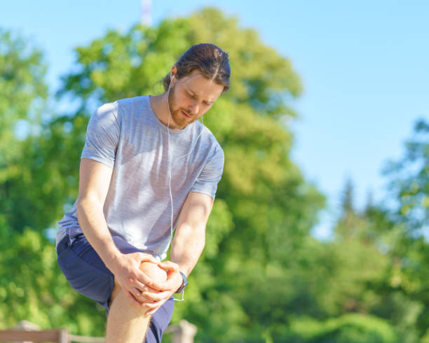 zmartwiony młody mężczyzna w sportowych ubraniach cierpiących na ból kolana podczas biegania na świeżym powietrzu - hand on knee audio zdjęcia i obrazy z banku zdjęć