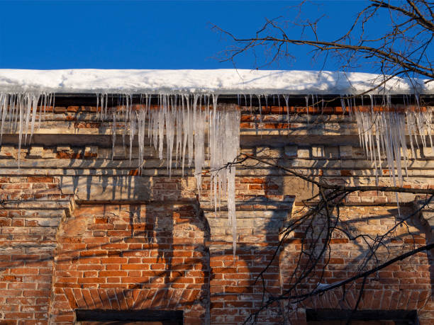 istock Icicles in sunlight hang on historic old building with a wall red damaged, dirty bricks. 1333544011