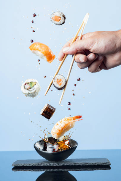 morceaux volants de sushi sur fond bleu.  format vertical. - hand rolled photos et images de collection