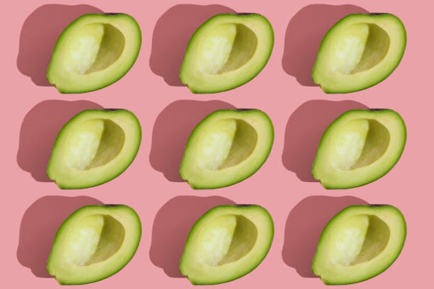istock Trending style pattern of half seedless green avocado on pink background with hard light. Creative food texture. 1333546279