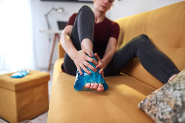 femme souffrant de douleurs au pied à la maison à l’aide d’un pack de gel de glace. - ice women ice pack physical injury photos et images de collection