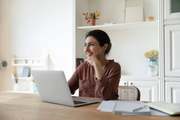istock Smiling Indian woman work on laptop dreaming planning 1333547953
