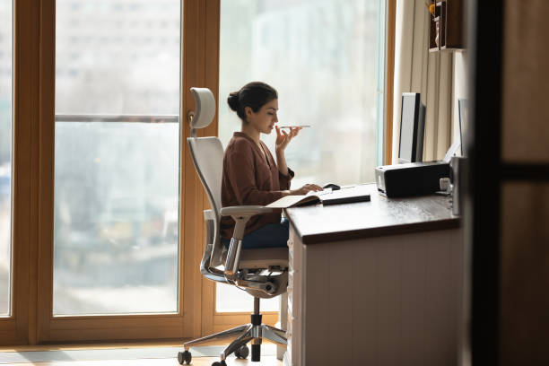 istock Young Indian woman work on PC talk on cellphone 1333548841