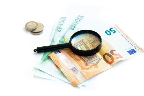 istock Magnifier, paper money and a stack of coins isolated on white background 1333548976