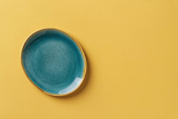 istock Turquoise teal oval ceramic plate over textured yellow background. Modern trendy colored crockery and tableware for stylish food design. Empty dishes. Copy space. 1333549249