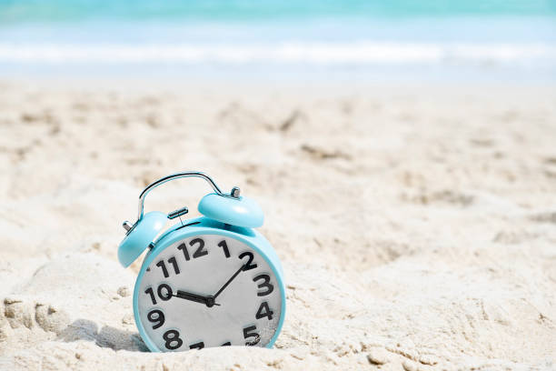 istock Blue alarm clock on the sand beach by the sea 1333550452