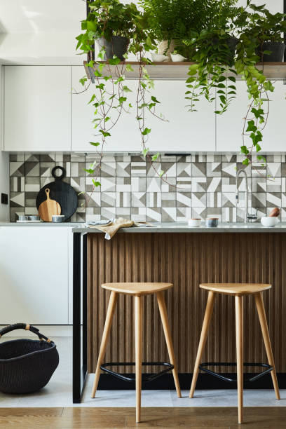 istock Stylish kitchen interior design with dining space. Workspace and kitchen island with kitchen accessories on the back ground. Creative walls with wooden panels. Minimalistic style an plant love concept. 1333553424