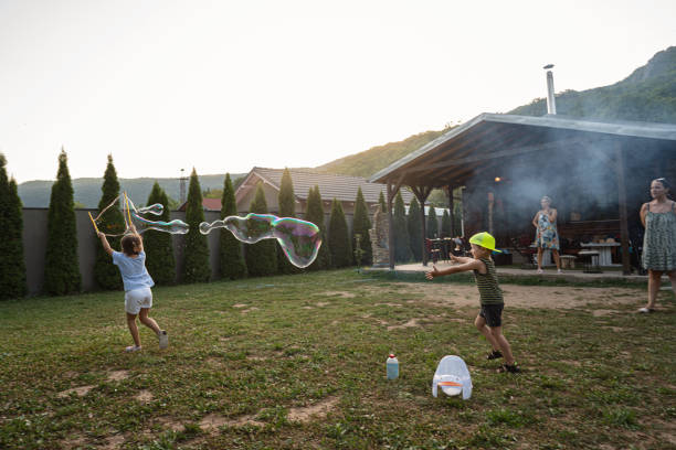 istock Playful cousins playing together and making a big soap bubble while their mother observing them 1333554330