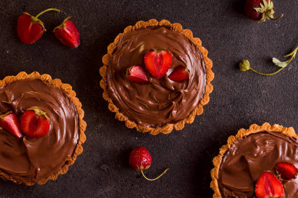 istock Three tarts with berries on a black background. view from above 1333555373