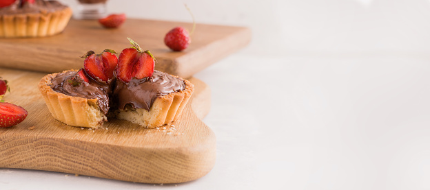 chocolate tart with strawberries on a white plate. Banner. Copy space