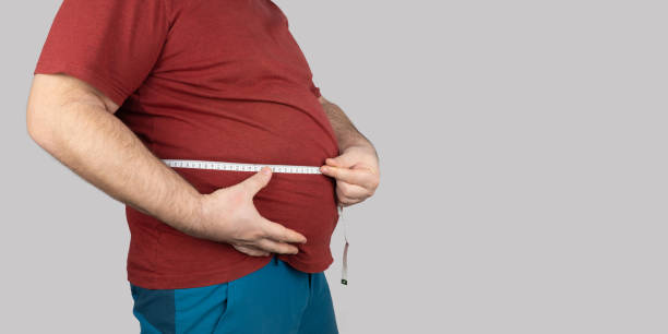 fat man measures the size of the abdomen with a centimeter measuring tape. people suffer from excess weight. banner, copy space fat man measures the size of the abdomen with a centimeter measuring tape. people suffer from excess weight. banner, copy space diet pills stock pictures, royalty-free photos & images