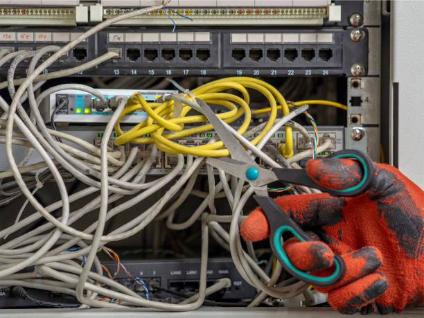 A man holds a pair of scissors and cuts the Internet cable (electrical wire) of the data server. The concept of blocking Computer Network, telecommunications broadcast, information technology. computer network router communication internet stock pictures, royalty-free photos & images