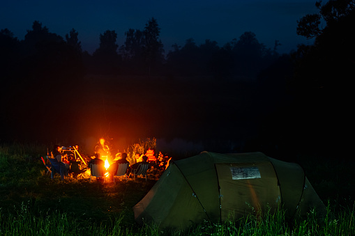 a group of people gather around a campfire at night on a hike