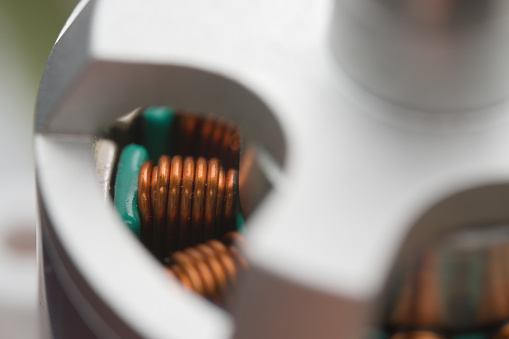 Bright close up of electromagnetic coils of copper, inside a brushless drone motor. Dust internally, and metal textures externally. Full frame image