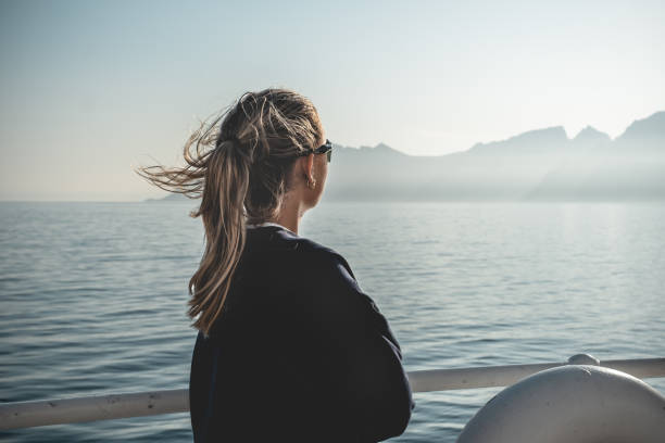 mujer joven con vistas al océano y la cordillera. - norway lofoten and vesteral islands sea mountain range fotografías e imágenes de stock