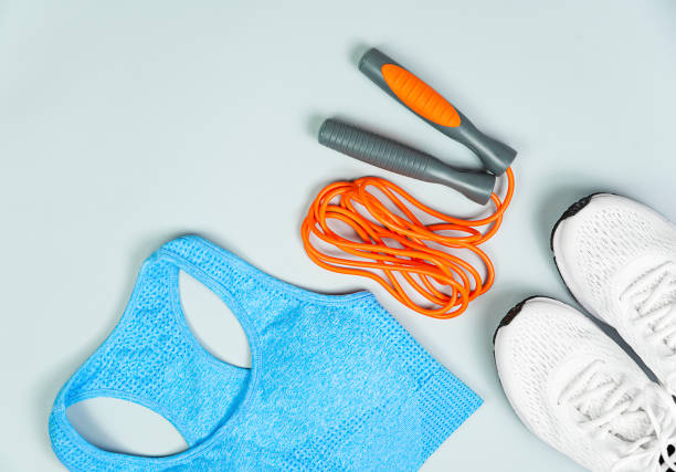 istock Workout clothes top orange, white sneakers, skipping rope on a gray background. 1333566959