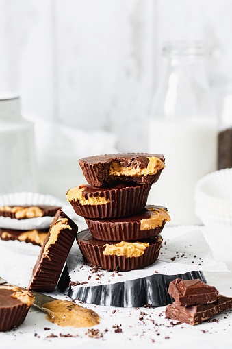 Mis-aligned stack of 4 peanut butter cups, make with chocolate, peanut butter and coconut oil, plus chocolate decoration, viewed from side