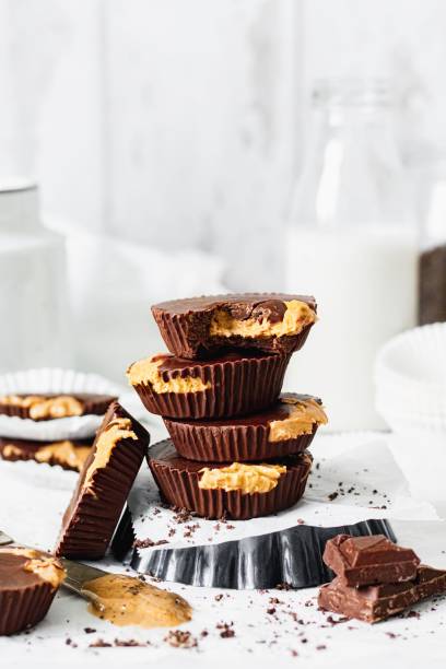 3 Ingredient Vegan Peanut Butter Cups Mis-aligned stack of 4 peanut butter cups, make with chocolate, peanut butter and coconut oil, plus chocolate decoration, viewed from side food styling stock pictures, royalty-free photos & images